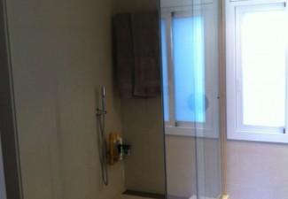 Mampara de ducha a medida con puerta corredera en vidrio laminado. 